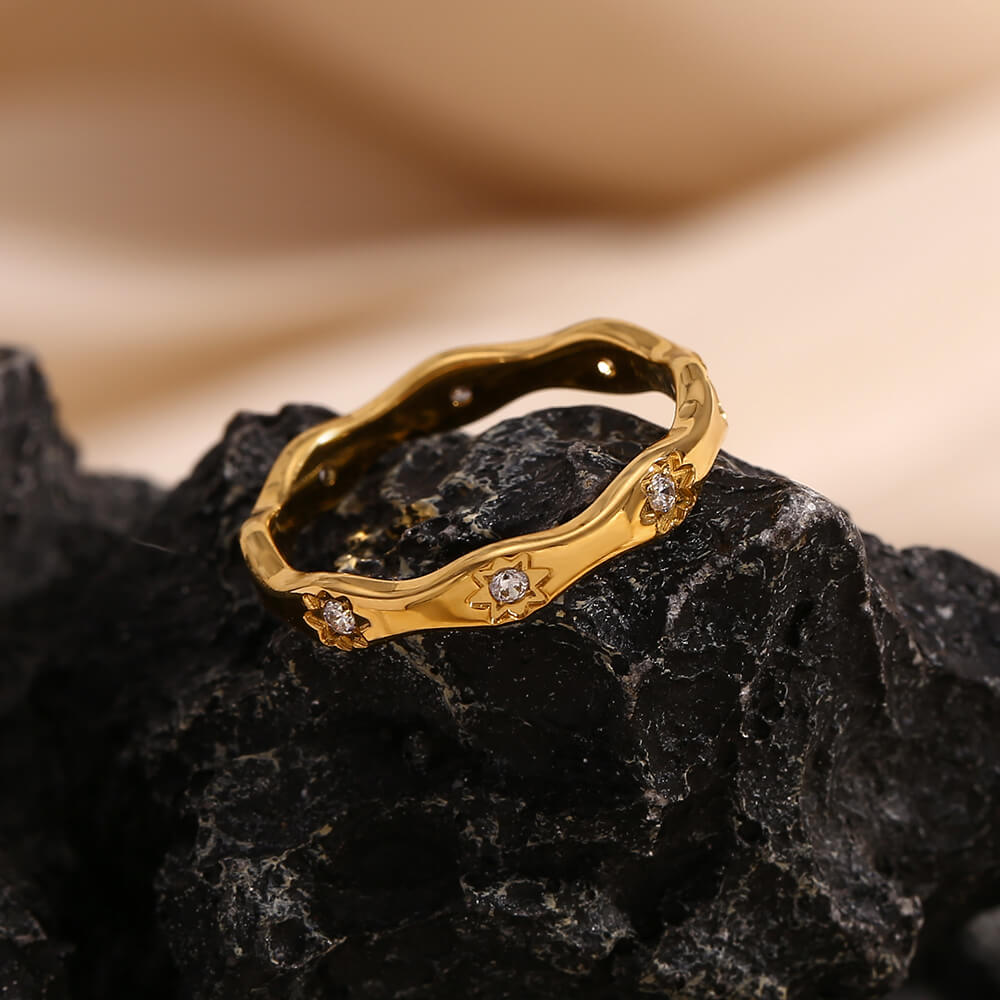Gold starburst cz ring bank on a black rock.