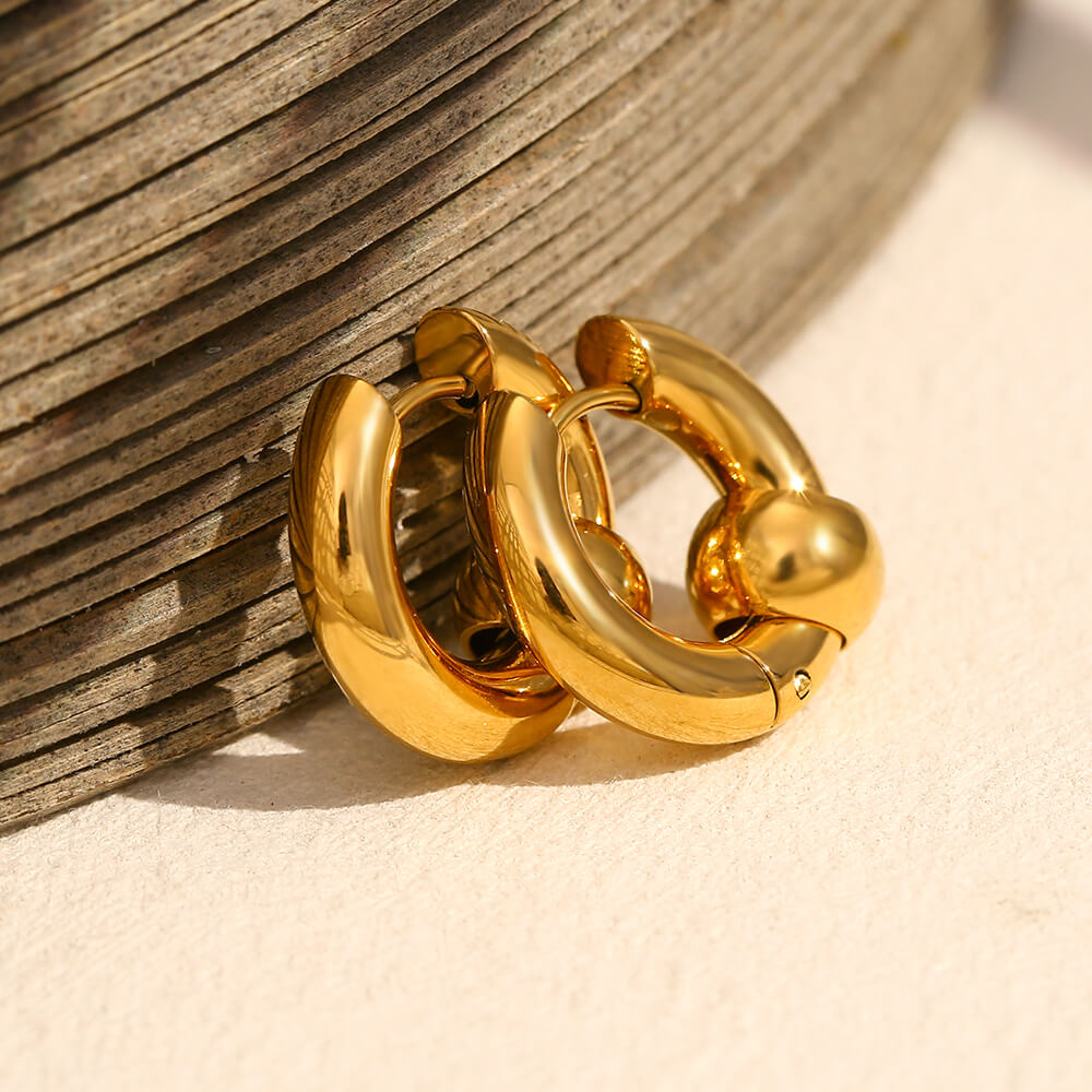 Gold hoop earrings on a wooden surface.