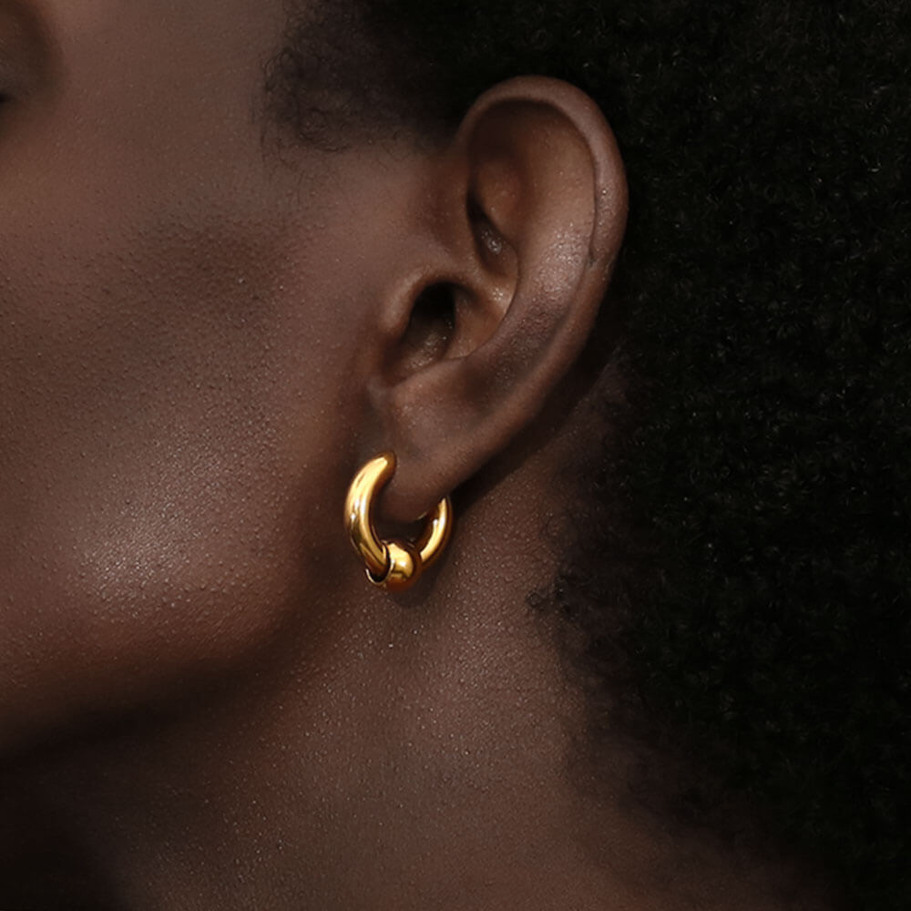 Gold hoop earring worn by a person with a dark skin tone.