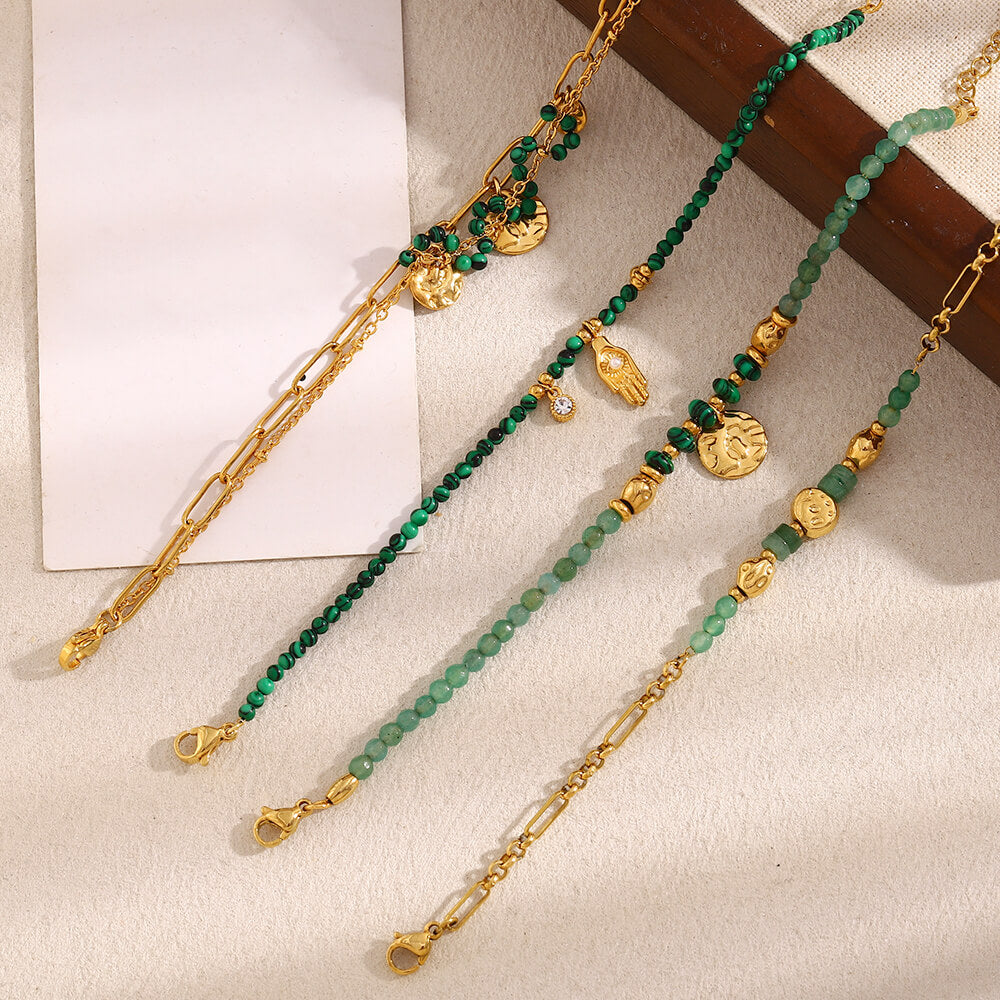 Gold and green beaded bracelets on a textured surface.
