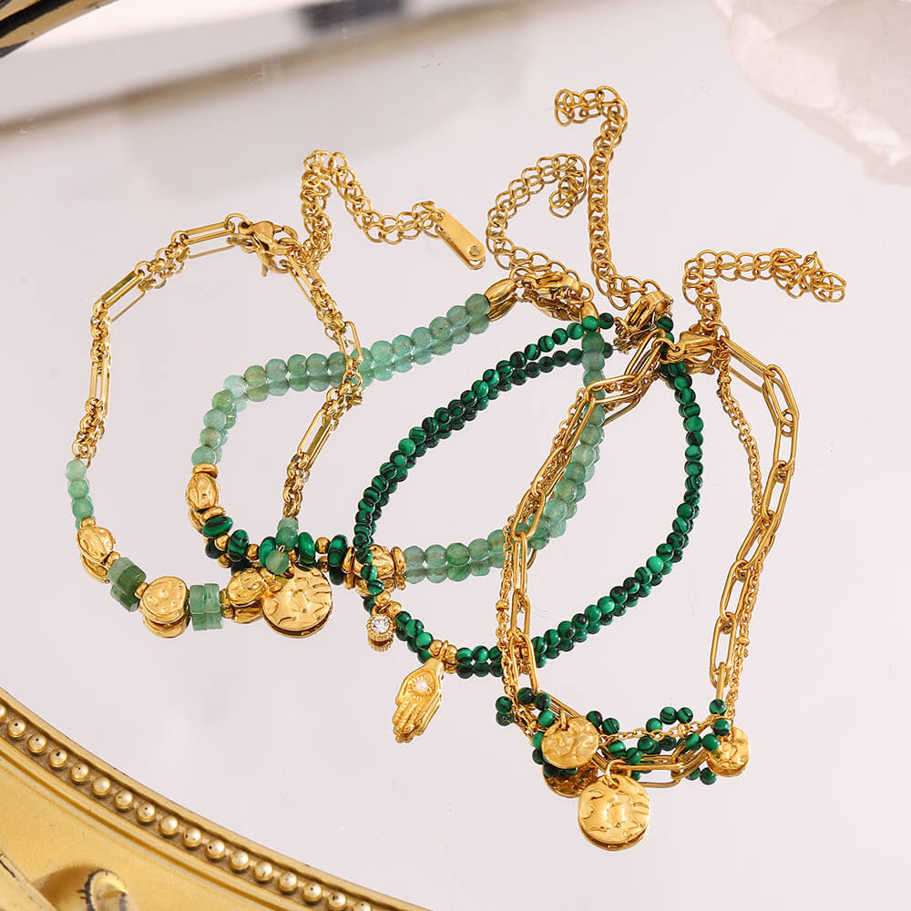 Gold and green beaded bracelets on a decorative surface.