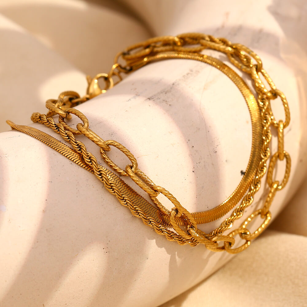 Three gold chain bracelet stack.