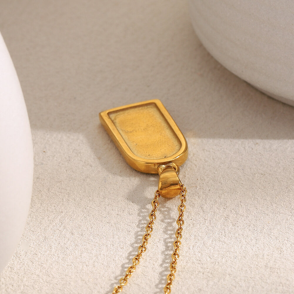 Back view of the Twinkling Moon Amulet pendant on a beige background.