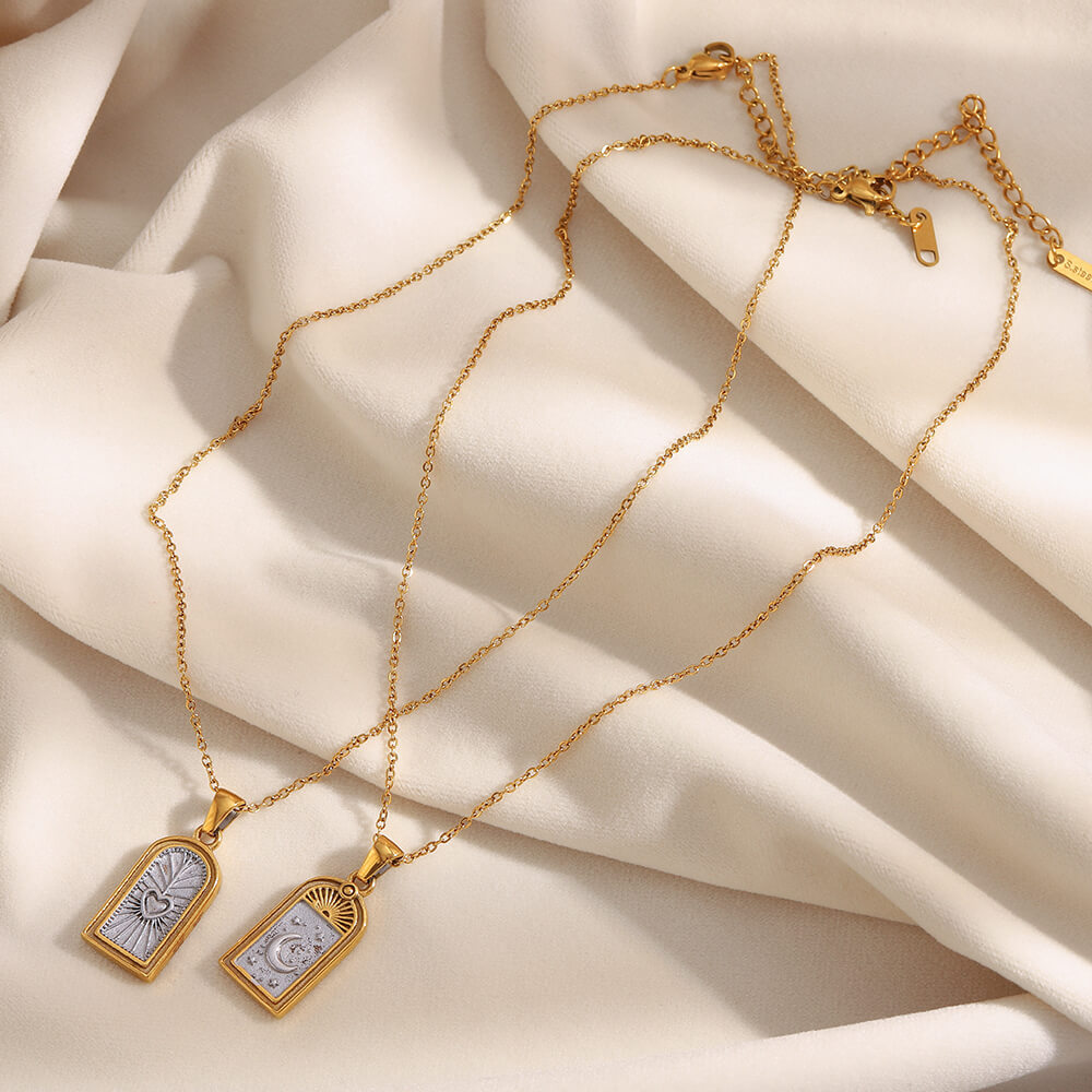 Gold necklaces with pendants on a beige fabric background.