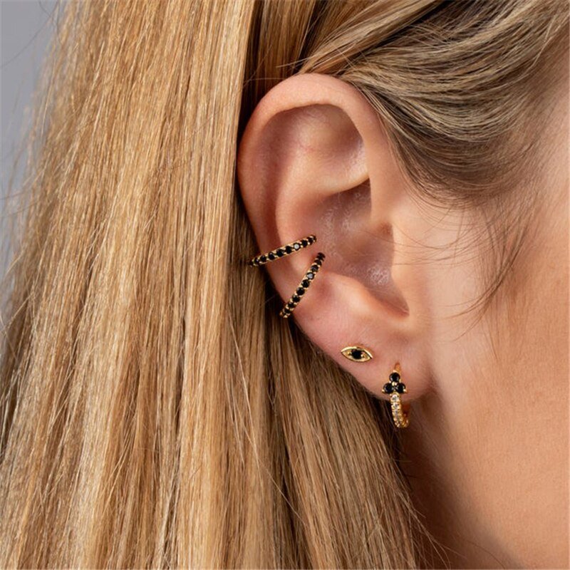 A model wearing multiple gold hoops with black CZ stones.
