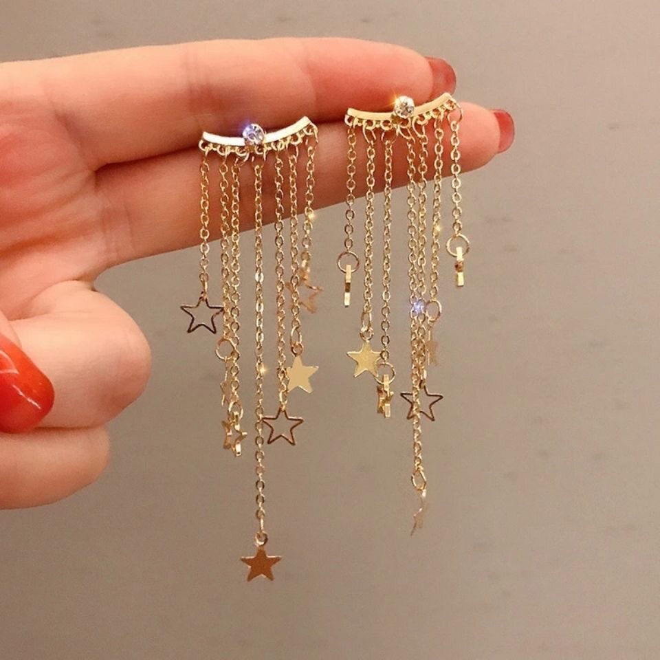 Closeup of the Gold Star Tassel Statement Earrings.