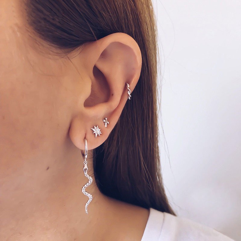 A model wearing multiple silver ear piercings.